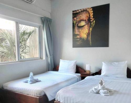 two beds in a room with a painting on the wall at Lotus Haven Villa in Siem Reap