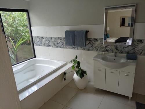 a bathroom with a tub and a sink and a mirror at Waterfront Guest House in Hartbeespoort