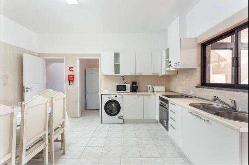 a white kitchen with a sink and a dishwasher at Aerya private rooms in Faro