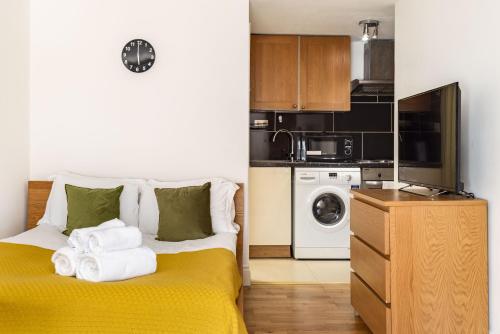 une petite chambre avec deux lits et une cuisine dans l'établissement South Kensington Courtfield Gardens studio, à Londres
