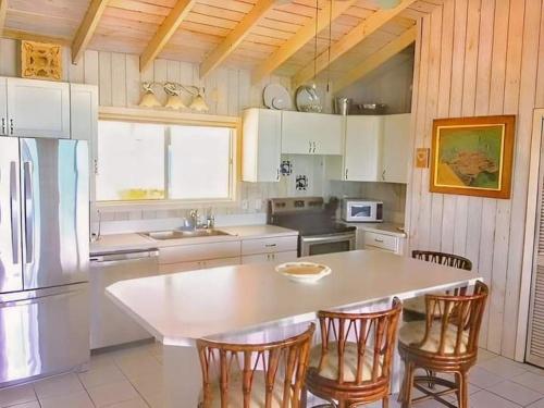 cocina con mesa, sillas y nevera en Sea Smile, en Staniel Cay