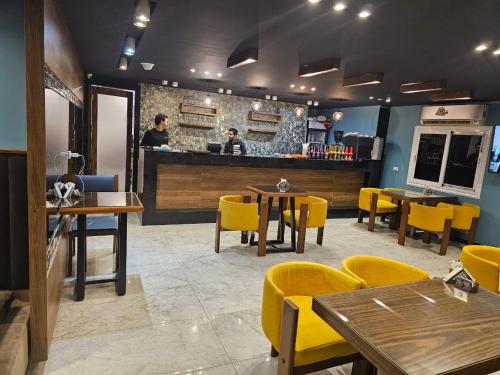 a restaurant with tables and yellow chairs and a counter at Royal Garden Hotel & Restaurant in Cairo