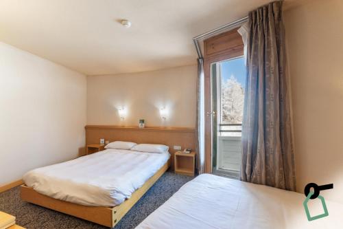 a bedroom with two beds and a large window at HOTIDAY Hotel Sestriere in Sestriere