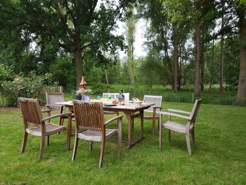 een houten tafel en stoelen in het gras bij Casa Kakelbos in Rotselaar