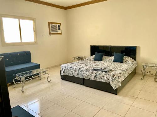 a bedroom with a bed and a blue couch at ستوديو كبير غرفة و حمام بمكيف غسالة تلفاز واي فاي in Al-Salam