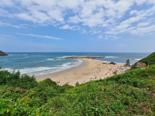 a beach with people on the sand and the ocean at Marina House in Pechón