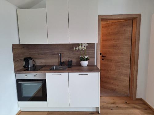 eine Küche mit weißen Schränken und einer Holztür in der Unterkunft Exklusiv Appartement in Innsbruck