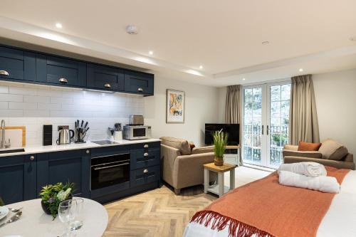 a kitchen and living room with blue cabinets and a couch at Rock Mill Apartment 16 in Stoney Middleton