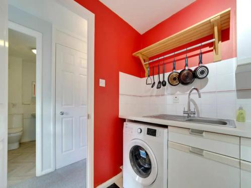 a kitchen with a washing machine and a red wall at Pass the Keys Renovated Sunny Home Pass the Keys in Cambridge