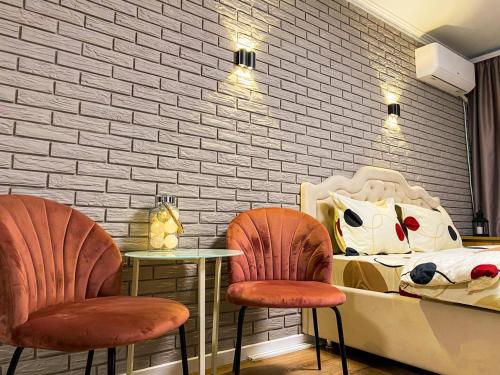 une chambre avec deux chaises, un lit et un mur de briques dans l'établissement Sunny Apartment, à Chişinău