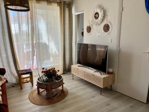 een woonkamer met een flatscreen-tv en een tafel bij Appartement vue océan in Capbreton