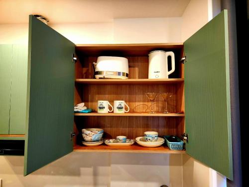 a pantry with green doors and cups and plates at Mi Amor Luxury Island Apartment - 3 minutes to the beach in Phu Quoc
