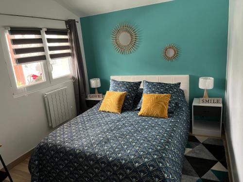 a bedroom with a bed with blue walls and yellow pillows at Maison « jardin la cigogne » in Sainte-Croix-en-Plaine