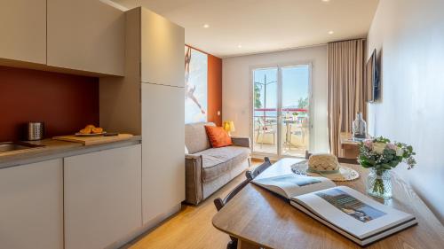 a kitchen and living room with a table and a couch at Résidence Kaliopé in Le Lavandou