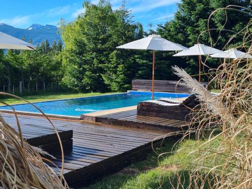 ein Pool mit einer Holzterrasse und einem Sonnenschirm in der Unterkunft Las Nubes in El Bolsón