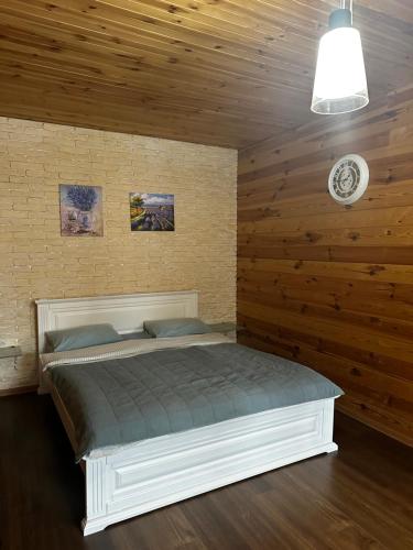 ein Schlafzimmer mit einem Bett in einer Holzwand in der Unterkunft Ранчо, Дом для релакса в окружении леса и озёр in Kolonshchina