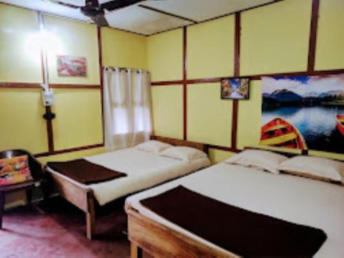 a bedroom with two beds and a table with a lamp at Nature's Hub Homestay Pasighat in Pāsighāt