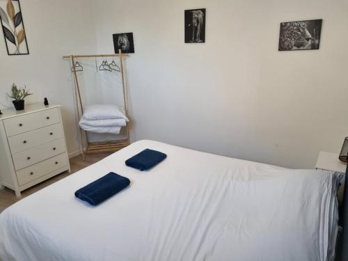 ein Schlafzimmer mit einem weißen Bett mit zwei blauen Handtüchern darauf in der Unterkunft Appart'hotel SOLESMES in Solesmes