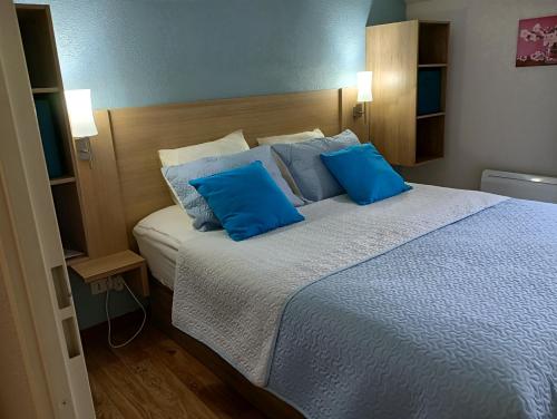 a bedroom with a large bed with blue pillows at T2 Calme assuré face à la pique les Ramel in Luchon