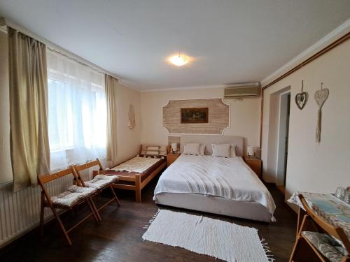 a bedroom with a bed and two chairs and a window at Villa Sunset in Palić