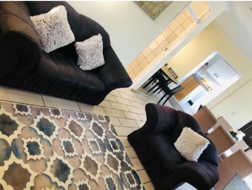 a living room with two leather couches and a rug at Serenity Cottage in Benoni