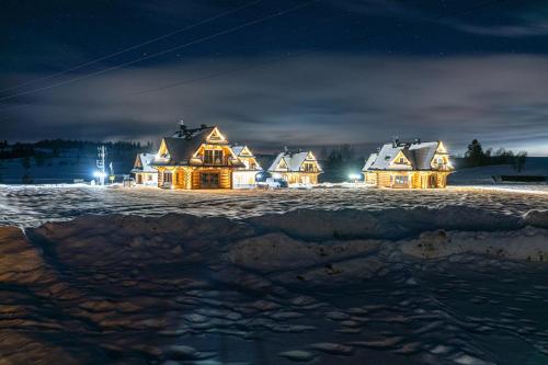 un groupe de maisons dans la neige la nuit dans l'établissement Jagodowa Osada, à Dzianisz