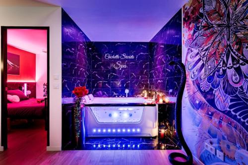 a bathroom with a tub with a purple wall at Cachette Secrète & SPA Narbonne in Narbonne