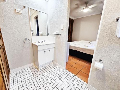uma casa de banho com um lavatório, um WC e uma cama em Royal Palm Villas em Cairns