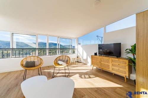 ein Wohnzimmer mit einem TV, Stühlen und Fenstern in der Unterkunft la grande vue exceptionnelle wifi in Bagnols-en-Forêt