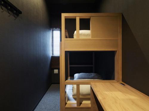 9 C Hotel Asahikawa في اساهيكاو: سرير بطابقين خشبي في الغرفة