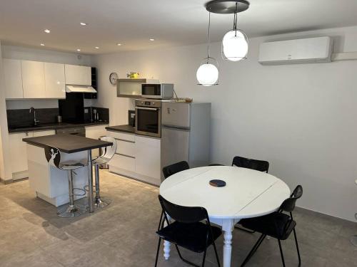 - une cuisine avec une table et une table et des chaises blanches dans l'établissement APPARTEMENT RENOVE T4 - 6 PERSONNES AVEC PARKING ET JARDIN, au Grau-du-Roi