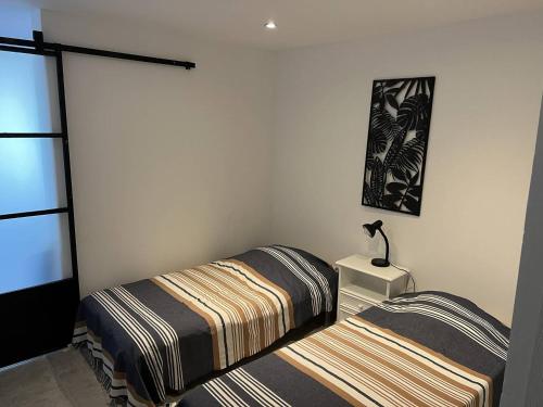 une chambre avec deux lits et une lampe sur une table dans l'établissement APPARTEMENT RENOVE T4 - 6 PERSONNES AVEC PARKING ET JARDIN, au Grau-du-Roi