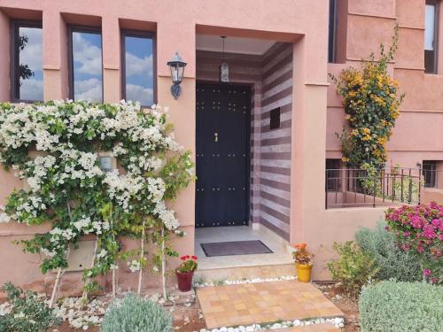 een roze huis met een zwarte deur en bloemen bij TOP Villa Pavillon dans Golf à 20 min de Marrakech in Sraghna