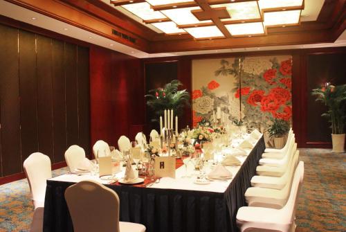 una mesa larga en una habitación con sillas blancas en Howard Johnson Tropical Garden Plaza Kunming, en Kunming