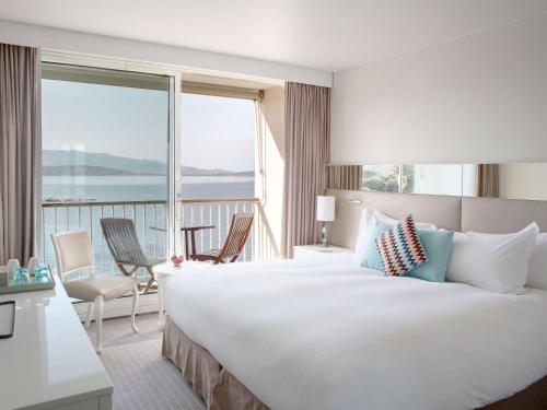 アジャクシオにあるソフィテル ゴルフ デジャッシォ タラサ シー ＆ スパの大きなベッドと大きな窓が備わるホテルルームです。