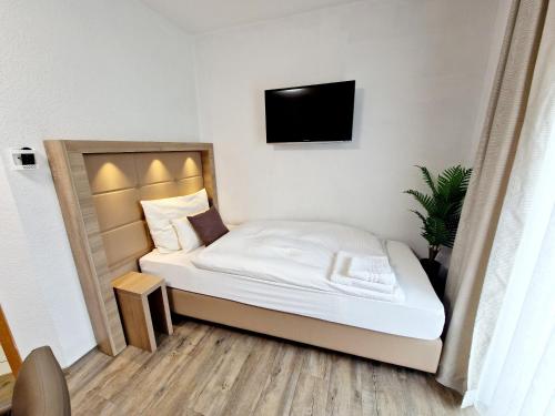 a small bedroom with a bed and a tv on the wall at Hotel Rheintal in Kappel-Grafenhausen