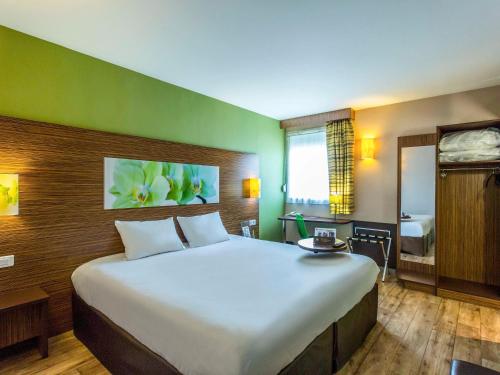 a bedroom with a large bed and a bathroom at Hôtel Ibis Styles Bourges - Piscine extérieure chauffée - Restaurants à proximité in Bourges