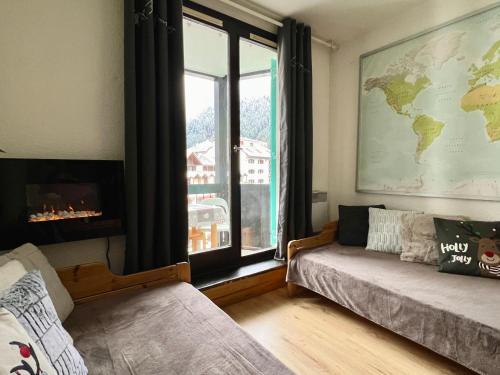 ein Wohnzimmer mit einem Fenster, einem Sofa und einer Karte in der Unterkunft Le Balme Studio WiFi/Parking/Balcony in Chamonix-Mont-Blanc