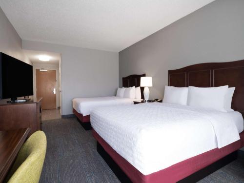 a hotel room with two beds and a flat screen tv at Hampton Inn Deerfield Beach in Deerfield Beach