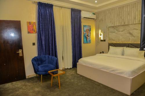 um quarto com uma cama e uma cadeira azul em SS3 Jabi Hotel em Abuja