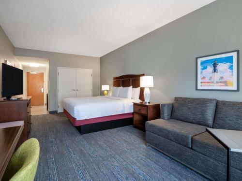 a hotel room with a bed and a couch at Hampton Inn Deerfield Beach in Deerfield Beach