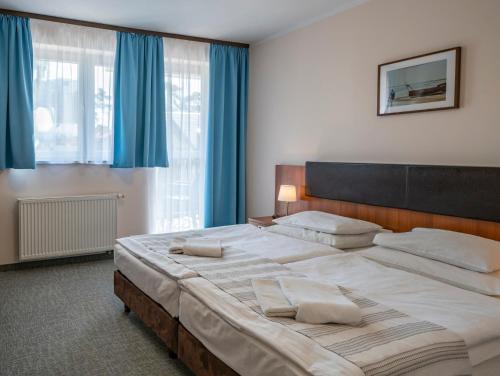 a bedroom with a large bed with blue curtains at Maximus Spa in Dziwnówek
