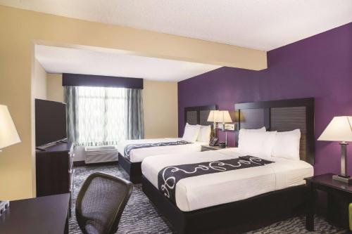 two beds in a hotel room with purple walls at La Quinta by Wyndham Clearwater South in Clearwater