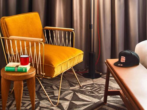 a yellow chair sitting in a room with a hat at Mama Shelter Prague in Prague