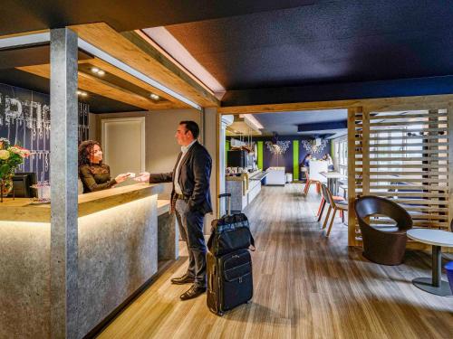 a man with a suitcase standing at a bar with a woman at Ibis budget Saint-Étienne stade in Saint-Étienne