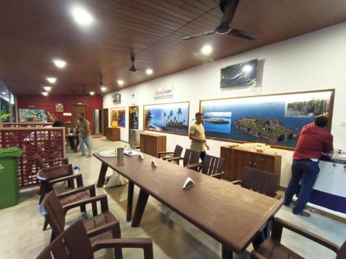 restauracja z dużym drewnianym stołem i krzesłami w obiekcie Srushti Sea Villa Resort w mieście Diveagar