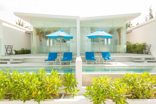 a pool with blue chairs and umbrellas at Explorar Koh Samui - Adults Only Resort and Spa in Mae Nam