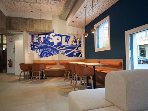 una sala da pranzo con tavoli, sedie e parete blu di Ibis budget Vitoria Gasteiz a Vitoria-Gasteiz
