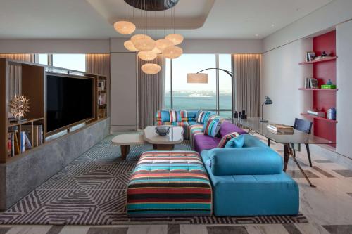 a living room with a couch and a tv at Andaz Doha, A Concept by Hyatt in Doha