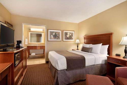a hotel room with a bed and a flat screen tv at Baymont by Wyndham Culpeper in Culpeper